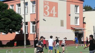 Uczniowie grają w piłkę nożną na boisku pod szkołą