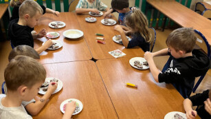 Dzieci siedzące przy stole i dekorujące pierniczki