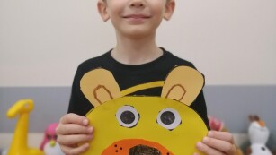 Chłopiec prezentuje swoją maskę misia.