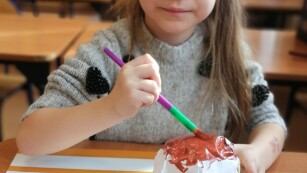 Dziewczynka malująca papierowego pączka farbami