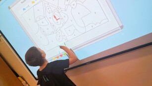 Chłopiec wykonujący zadania na tablicy interaktywnej