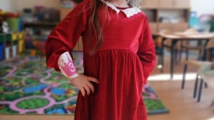 Dziewczynka w czerwonej sukience pozuje do zdjęcia