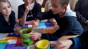 Uczniowie macczają kukurydziane chrupki w ciepłej czekoladzie.
