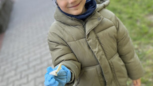 Chłopiec w brązowej kurtce podczas sprzątania świata