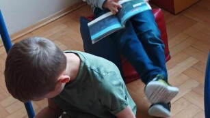 Dwóch chłopców siedzi na pufach i oglądają lub czytają książki.