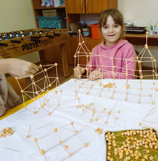 Dziewczynka prezentująca swoją budowlę z ciecierzycy