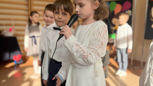 Dziewczynka w białej sukience mówiąca wiersz do mikrofonu