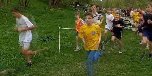 Uczniowie biegną wyznaczona trasą po trawie.