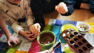 Uczeń nalewa płynną czekoladę do foremek w kształcie serduszek.